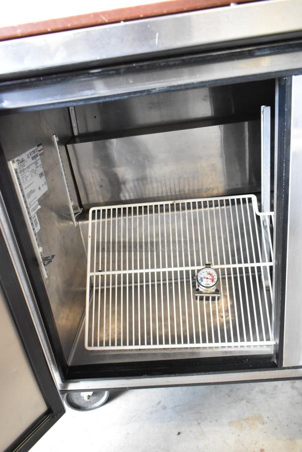 True TSSU-72-18-ST stainless steel pizza prep table, features interior shelving, commercial casters, and visible model label.
