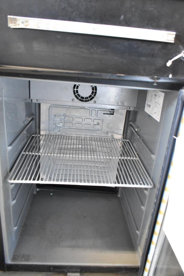 Metal mini cooler merchandiser, 115 volts, 1 phase, includes wire shelf, interior fan, visible label with specifications.