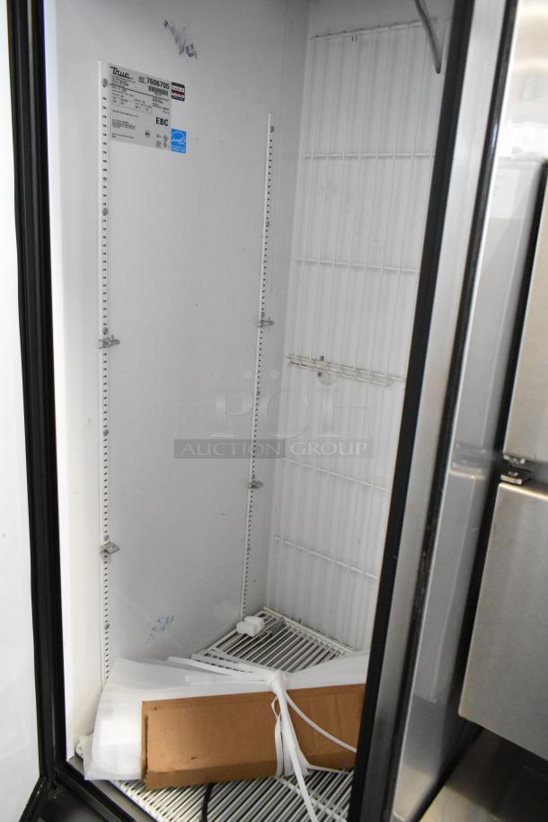 True T-23F stainless steel commercial freezer with poly-coated racks, shown open with interior details visible. Model and serial labels present.
