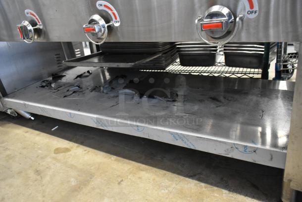 Stainless steel commercial gas-powered 4 burner steam table with under shelf. Features control knobs, used condition.