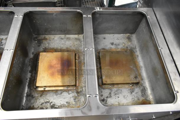 Stainless steel commercial gas-powered steam table with 4 burners and under shelf, worn condition, visible heating elements.