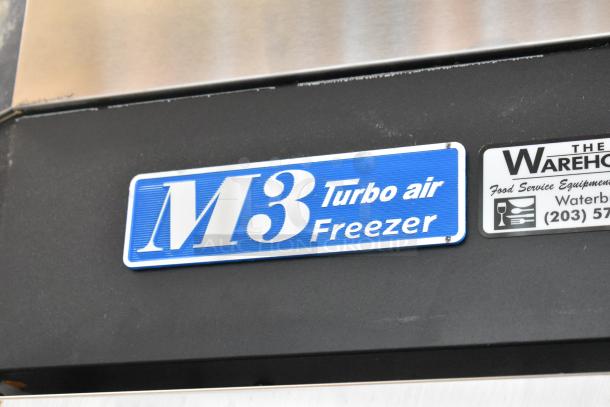 Turbo Air M3F47-2 stainless steel freezer with 2 doors, poly racks, commercial casters. 115V, 1 phase. Tags show model info.