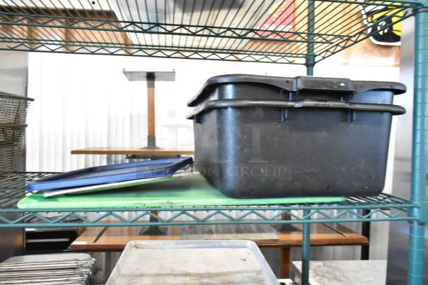 Three-tier shelving unit with metal baking pans, stainless steel drop-in bins, and poly bus bins. Used condition.