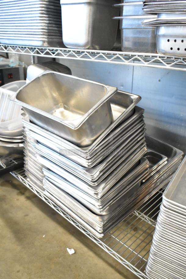 Tiered lot of stainless steel drop-in bins, metal baking pans, and bowls in good condition, stacked on shelves.