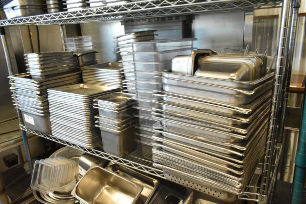 Auction lot of stainless steel drop-in bins, metal baking pans, and poly bins on metal shelves, items in good condition.
