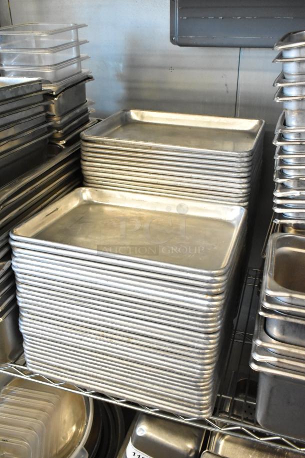 Stack of metal baking pans and poly drop-in bins on shelves; mixed-use storage and kitchenware in used condition.