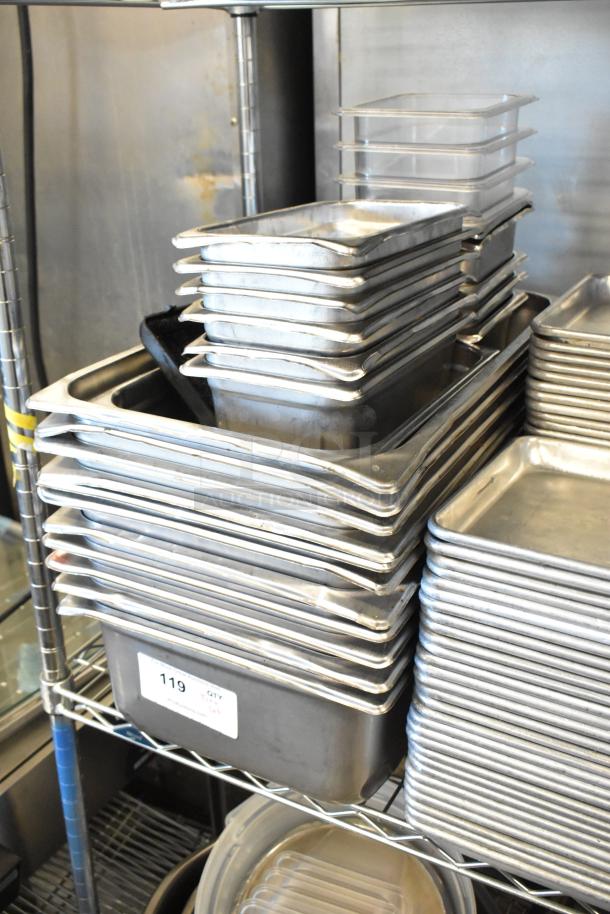 Auction lot of stainless steel drop-in bins, metal baking pans, and poly drop-in bins on a metal shelf, all in used condition.