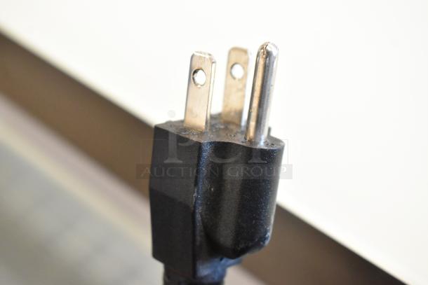 Close-up of a three-prong electrical plug, associated with the Avantco 193BC60HCW bakery display case.
