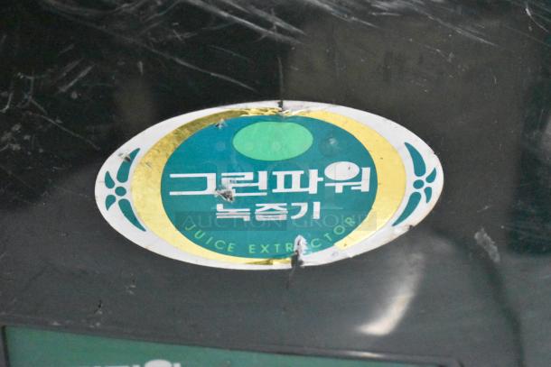 Countertop juice extractor juicing machine with visible label indicating "Juice Extractor" in Korean and English; black exterior.