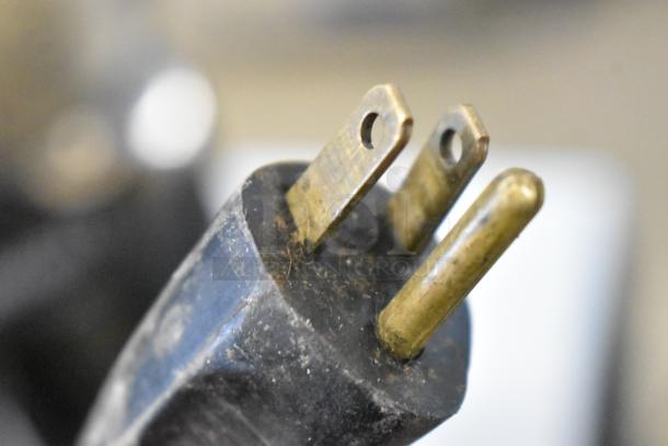 Close-up of a power plug for the Rossi RR45 Espresso Bean Grinder, showing gold prongs and black casing.