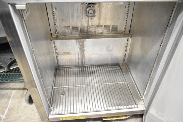 Silver King SKF27 stainless steel undercounter freezer interior with wire shelf, visible wear marks, 115 volts, 1 phase.