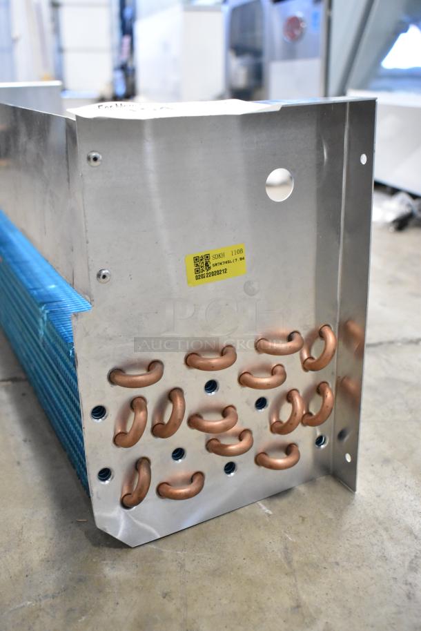 BRAND NEW SDKH 5R7K745L evaporator coil with visible scratch and dent. Features copper tubing and a yellow label with QR code.
