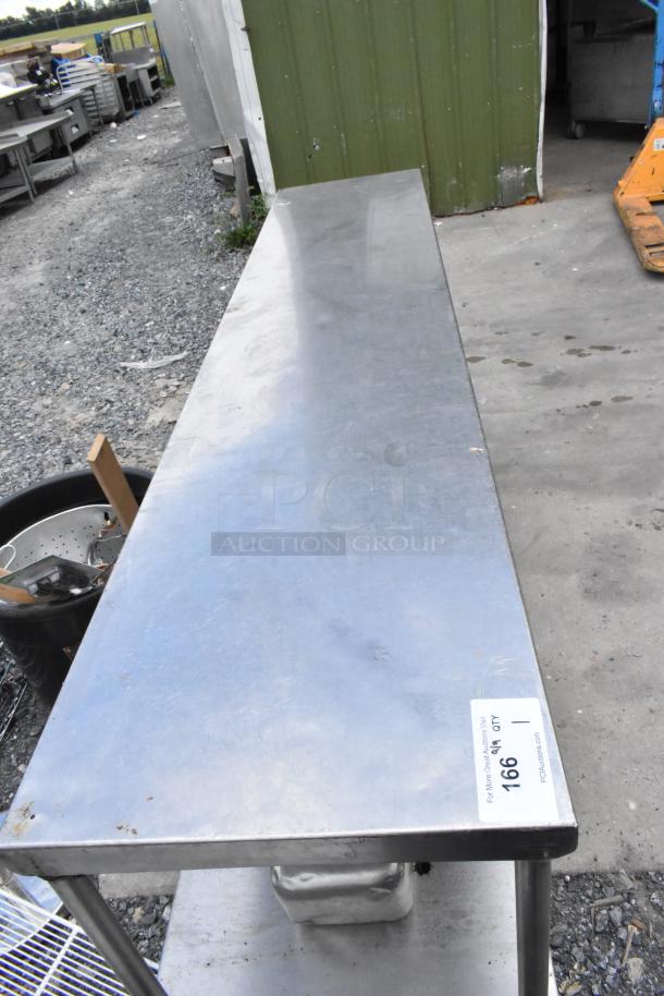 Stainless steel table with two under shelves, slight surface wear, industrial setting, auction tag reads "1669".