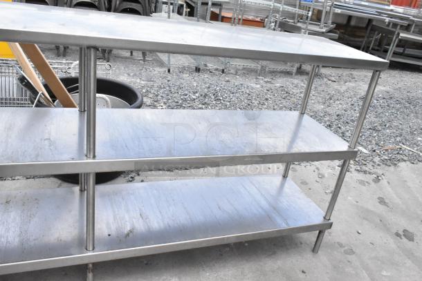 Stainless steel table with two under shelves, industrial-grade. Slight surface wear, ideal for kitchen or storage use.