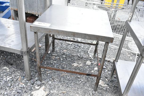 Stainless steel equipment stand with rusting legs, used condition. Tabletop has a label with numbers "167 A4 9/1."