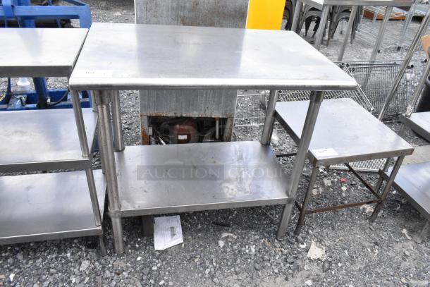 Stainless steel table with metal under shelf, showing moderate wear, ideal for industrial or kitchen use.