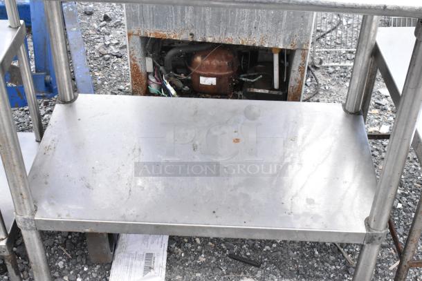 Stainless steel table with metal under shelf, showing signs of rust and wear, suitable for industrial use.