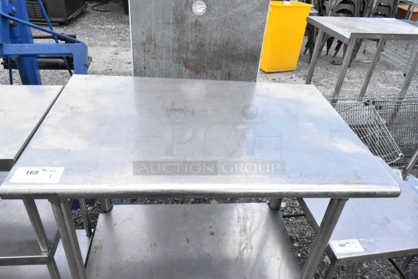 Stainless steel table with metal under shelf, industrial setting, visible surface wear, and price tag indicating QTY 1.