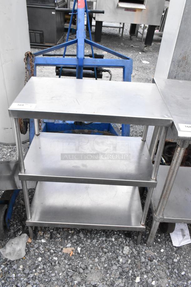 Stainless steel table with two under shelves, showing minor wear, label marked "169" on top corner. Perfect for industrial use.