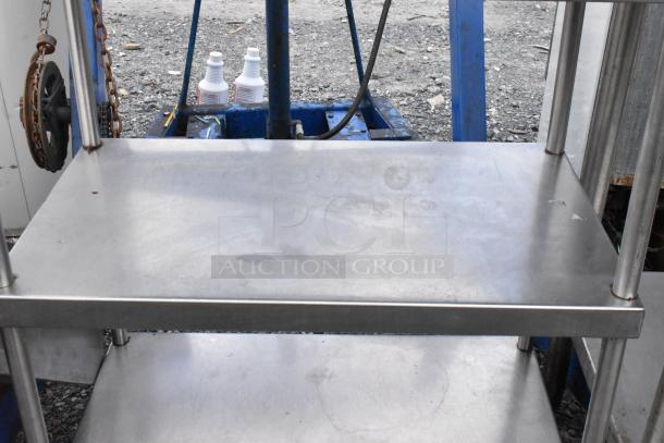 Stainless steel table with two under shelves, showing a sturdy metal frame and clean surfaces, ideal for industrial use.