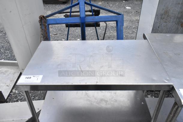 Stainless steel table with two under shelves, showing minor surface wear. Label indicating item number 169. Suitable for industrial use.