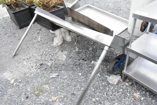 Stainless steel shelf with two legs, shown outdoors; appears in good condition, suitable for kitchen or storage use.