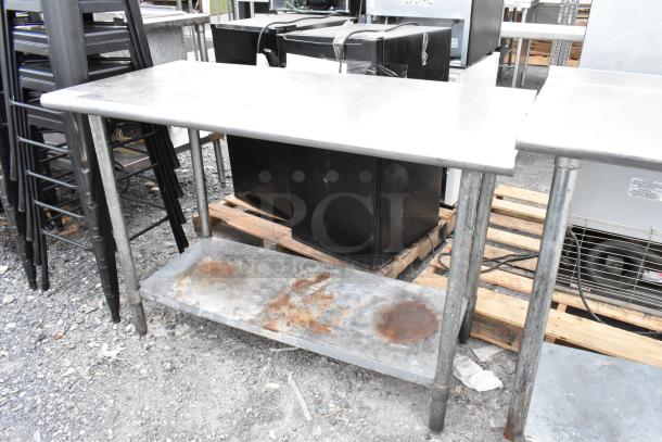 Stainless steel table with metal under shelf, showing some rust on the shelf, in used condition, ideal for industrial use.