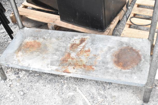 Stainless steel table with rusty metal under shelf, showing signs of wear. No visible brand or markings.