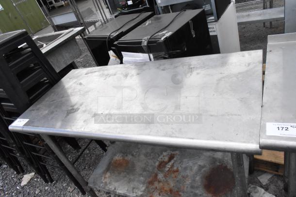 Stainless steel table with metal under shelf, showing wear and rust marks, ideal for workshop or industrial use.
