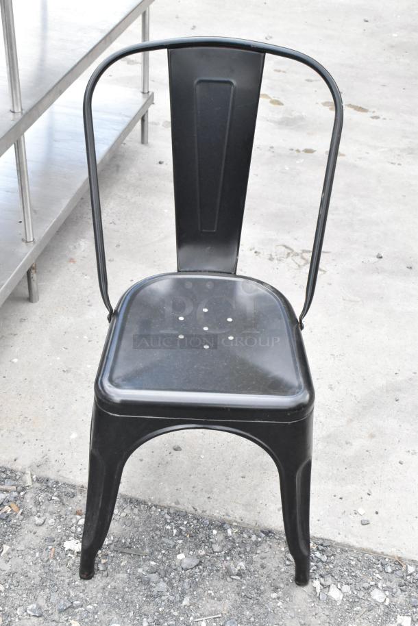 Black metal Tolix style chair, industrial design, visible wear, durable construction, ideal for modern spaces.