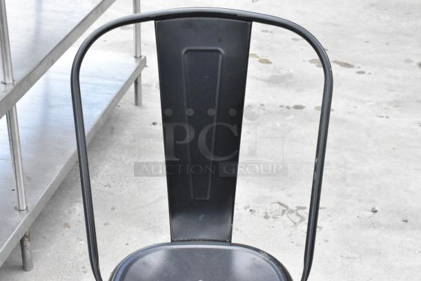 Black metal Tolix style chair, features industrial design, sturdy backrest, minimal wear. Part of 38-piece set.