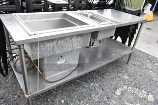 Stainless steel 2-well food warmer station with under shelf, showing signs of wear, includes electrical connections.