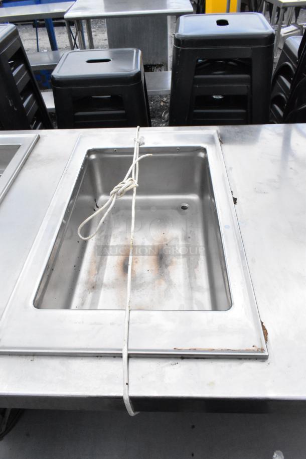 Stainless steel 2-well food warmer station with under shelf, showing signs of use. Rope and rust visible around edges.
