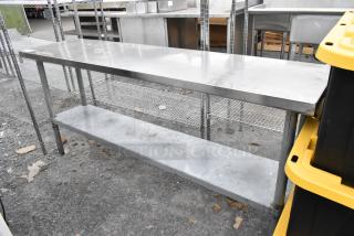 Stainless steel table with metal under shelf, in used condition, features a durable surface and wire support beneath.