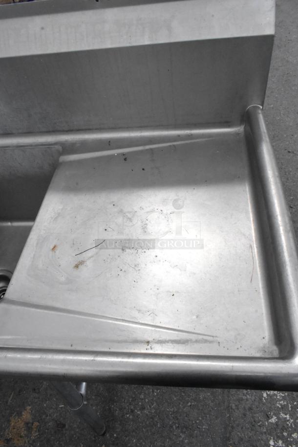 Stainless Steel 3 Bay Sink with dual drain boards, visible surface wear, ideal for commercial use.