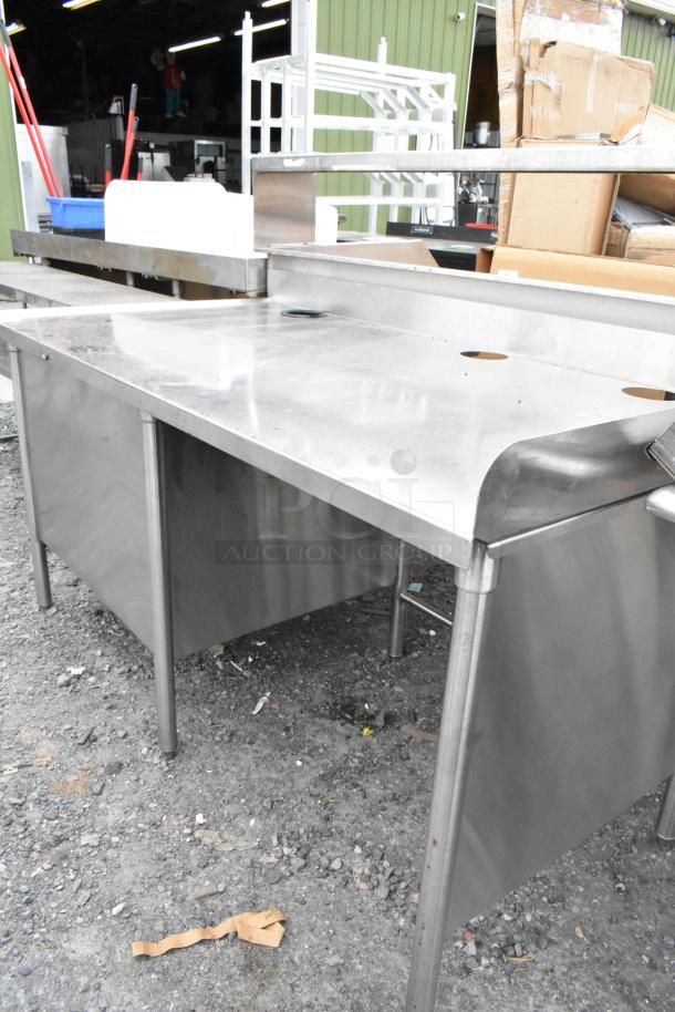 Stainless steel table with side under shelves, featuring a durable surface and sturdy legs. In good condition.