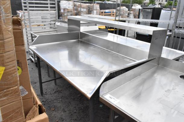 Stainless steel commercial table with raised edges, sturdy construction, ideal for food service. Slight wear visible.