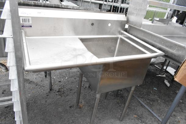 Yukon stainless steel commercial single bay sink with left side drain board, in used condition, visible product labels.