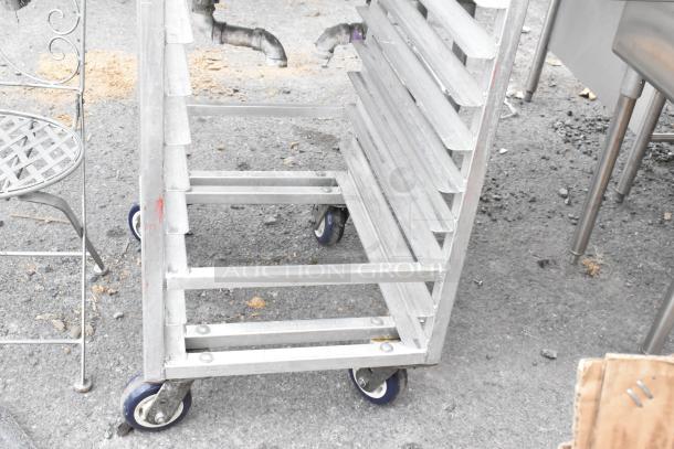 Metal commercial pan transport rack with multiple slots and commercial casters, ideal for kitchen use. Appears in good condition.