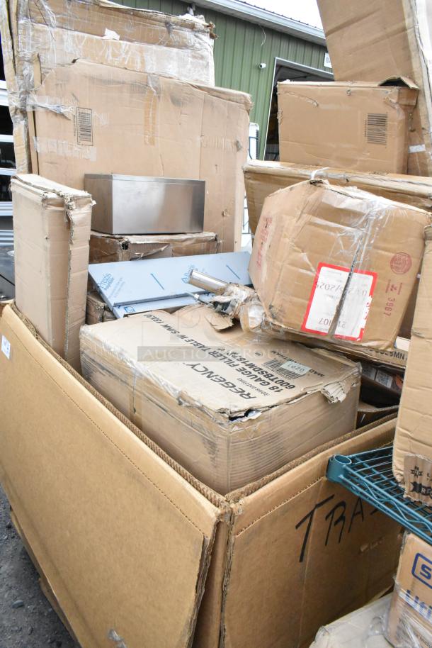 Boxes of new scratch and dent items including Regency stainless steel table and shelf, Watts grease trap, and Steelton shelf kit.