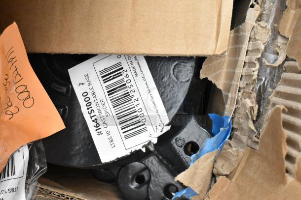Cardboard box revealing metal part with label "#164TS1000 LT&S10" and notes on orange paper, indicating new condition.