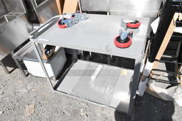 Gray metal 2-tier cart with commercial casters, brand new with scratch and dent. Durable design for versatile use.