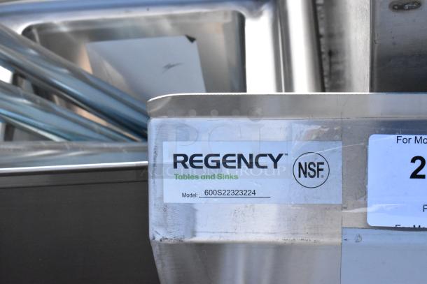 BRAND NEW Regency stainless steel 2-bay sink, model 600S22323224, with dual drain boards, minor scratches and dents.