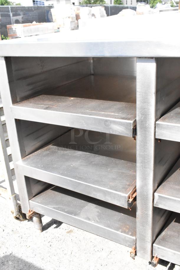 Stainless steel table with under shelves, featuring a durable construction. Good condition with some surface wear.