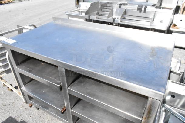 Stainless steel table with under shelves, industrial-grade, sturdy design, minor surface wear, ideal for kitchen or workspace.