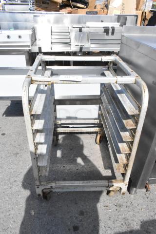 Metal pan transport rack on commercial casters, showing signs of rust, with multiple slots for pans. Label reads "227".