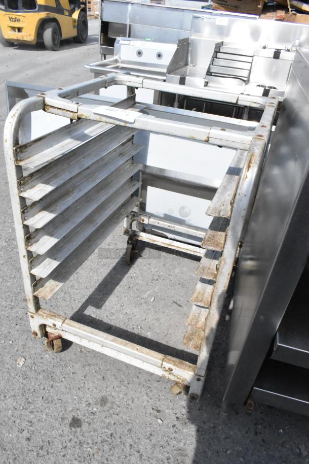 Metal pan transport rack with commercial casters, showing visible rust and wear. Designed for kitchen or industrial use.