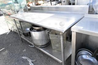 Stainless steel table with under shelf, includes skillets and stock pots. Excellent condition, sturdy, ideal for kitchen use.