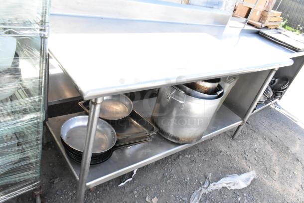 Stainless steel table with under shelf; includes skillets and stock pots. Ideal for kitchen use. Good condition.