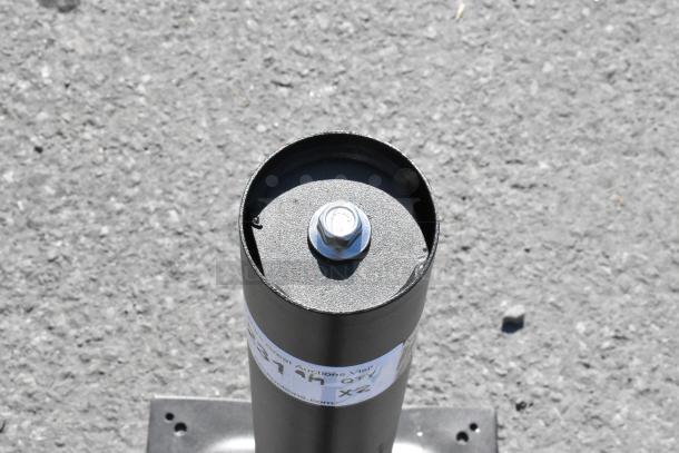 2 black metal table base columns, sturdy with mounting holes, label indicating auction details, good condition.